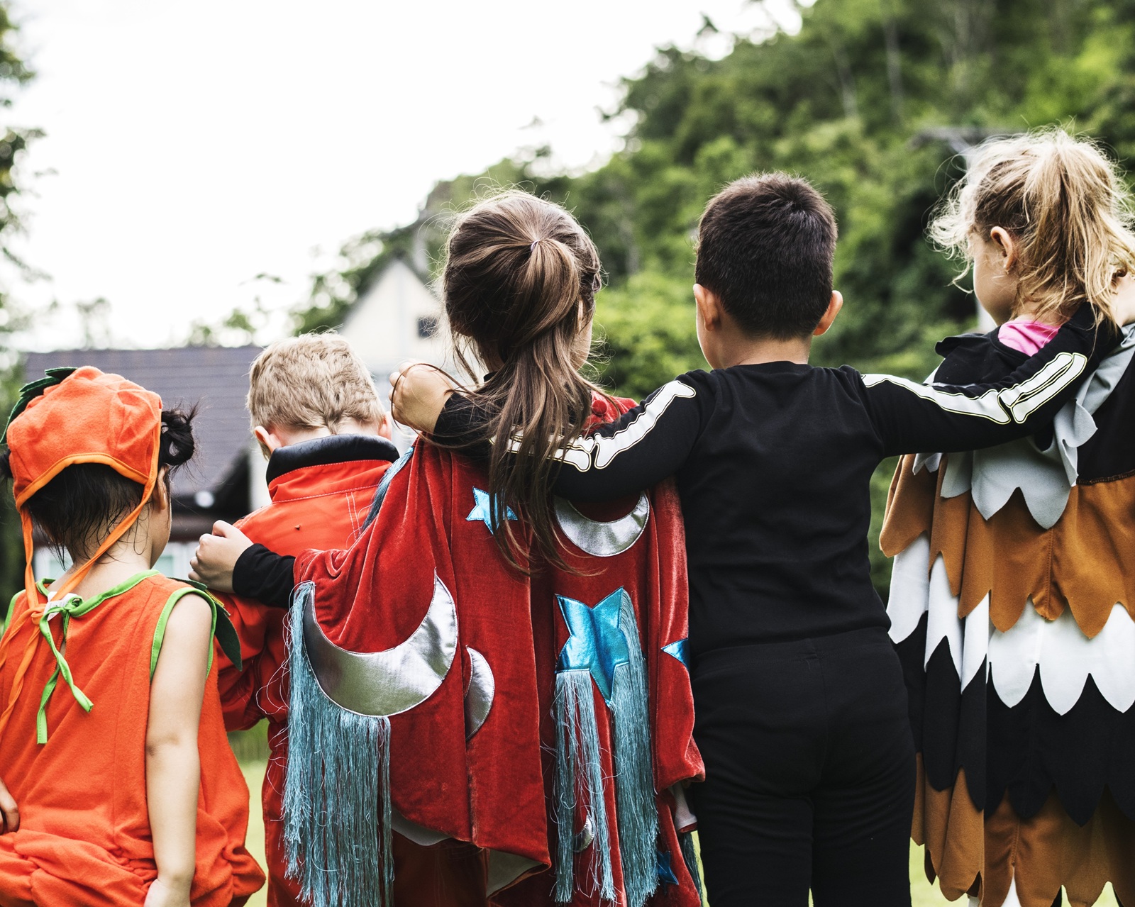 Enfants costumés de dos participant à une fête et partageant un moment convivial